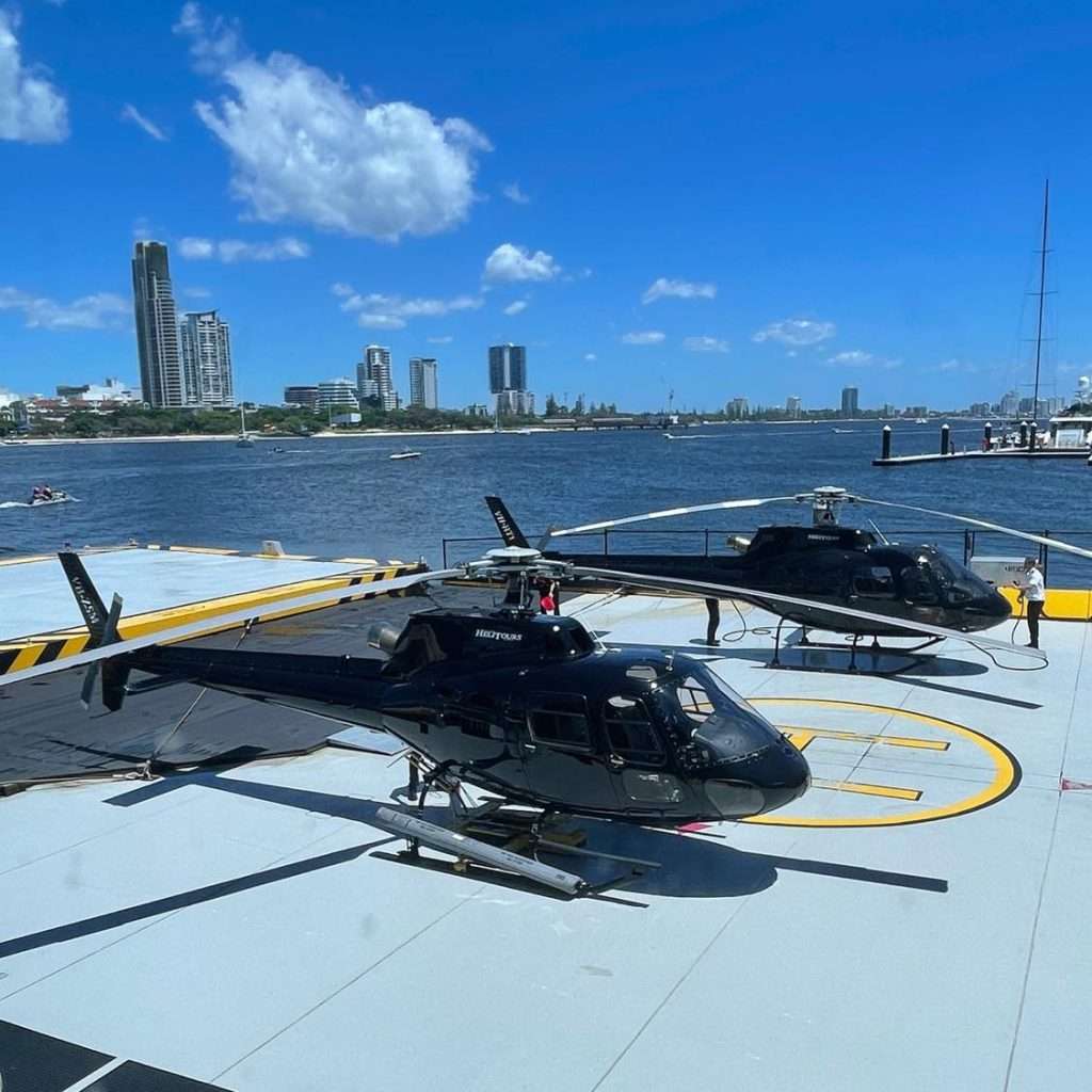 a group of black helicopters on to of a helipad near the coast